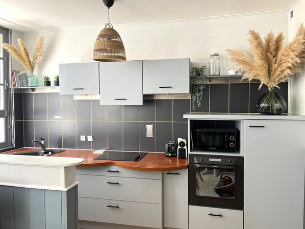 Una cocina moderna con armarios grises, encimera de madera y horno empotrado.