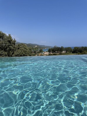 Clear turquoise water with visible ripples and a distant view of a coastal area with buildings and greenery. - New villa with large heated pool and sea view (Conca)