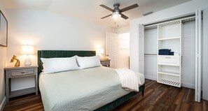 Een slaapkamer met een bed, nachtkastjes, een plafondventilator en een inloopkast.