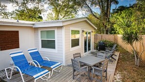 A small house with a deck, two blue lounge chairs, a table, and a barbecue grill. - Modern Farmhouse Retreat – Heated Pool & Close to Beaches! (Stuart)