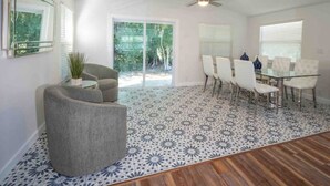 A spacious room with a dining area, a ceiling fan, and a large window providing natural light. - Modern Farmhouse Retreat – Heated Pool & Close to Beaches! (Stuart)