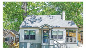 A single-story house with a front porch, a chimney, and a small deck.