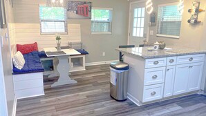 A modern kitchen with a central island, white cabinetry, and a dining area with a table and chairs.