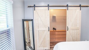 A bedroom with a large mirror, a sliding barn door closet, and a bed.