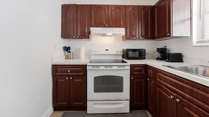 A compact kitchen with wooden cabinets, a white stove, a microwave, and a toaster. - Stay in this cozy and bright 2BR apartment, featuring a welcoming living room, modern décor, and plenty of natural light. Walk to Calle Ocho cafés, murals, and music, and reach Brickell in minutes. Perfect for families or groups exploring Miami (Miami)