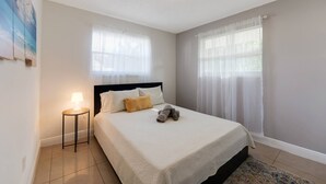 A neatly arranged bedroom with a bed, bedside lamp, and a window with sheer curtains. - Stay in this cozy and bright 2BR apartment, featuring a welcoming living room, modern décor, and plenty of natural light. Walk to Calle Ocho cafés, murals, and music, and reach Brickell in minutes. Perfect for families or groups exploring Miami (Miami)