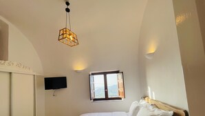 Ein Schlafzimmer mit Bett, Wand-Fernseher, Fenster mit Aussicht und einer Pendelleuchte.