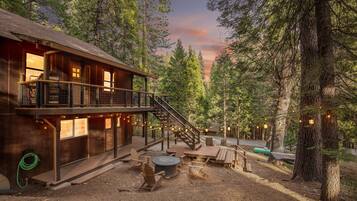A cabin with a deck, outdoor seating, and a fire pit.