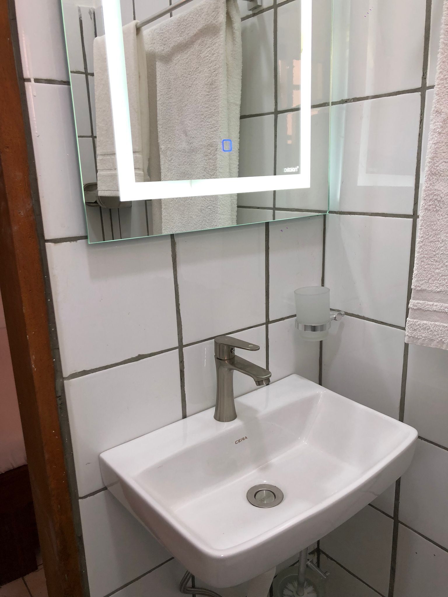 A bathroom with a white sink, a mirror, and a towel hanging on the wall.