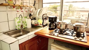 A kitchen with a gas stove, a sink, and a window with a view of buildings. - 1 Bed Studio Sleeps 2 - Canal Views, Balcony, Wifi (Douala)
