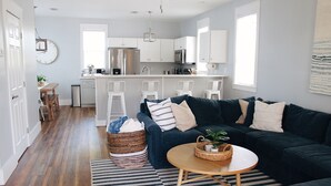 A modern living room with a dark blue sofa, a round wooden coffee table, and a striped rug.