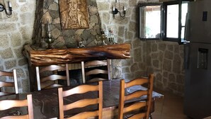 A rustic kitchen with a stone wall, wooden dining table, and chairs. - Caseddu in the shade of the Olive Trees, just a few steps from the sea. (Olmeto)
