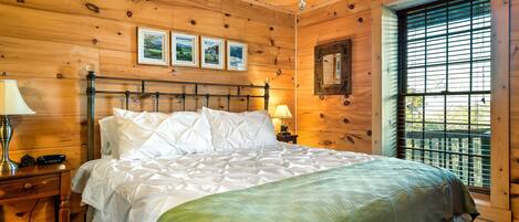 Un dormitorio con paneles de madera, una cama, lámparas de noche e imágenes enmarcadas en la pared.