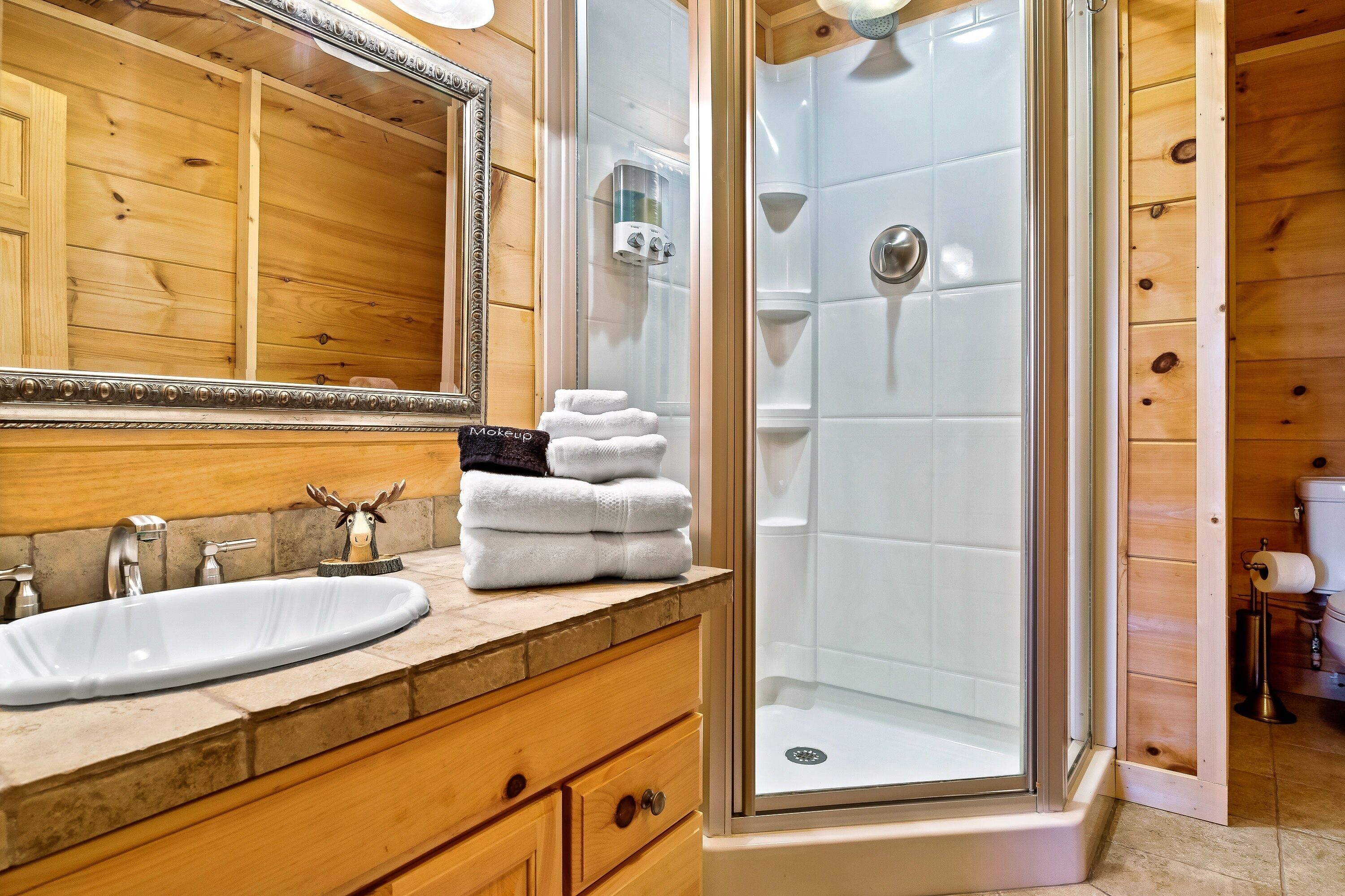 A bathroom with a wooden vanity, a sink, and a glass-enclosed shower.