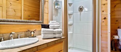 A bathroom with a wooden vanity, a sink, and a glass-enclosed shower.