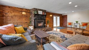 Una sala de estar acogedora con chimenea de piedra, paredes de madera y asientos cómodos.