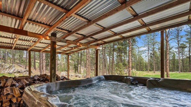 Un jacuzzi bajo una pérgola de madera con vistas al bosque.