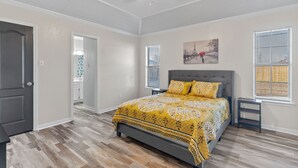 Une chambre à coucher avec un lit, un ventilateur de plafond, une fenêtre avec des stores et une porte.