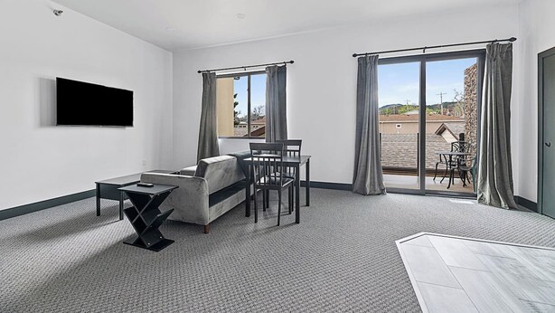 A modern living room with a sofa, a small table, and a TV mounted on the wall. - Downtown Executive Apartment - Pyrite (Spearfish)