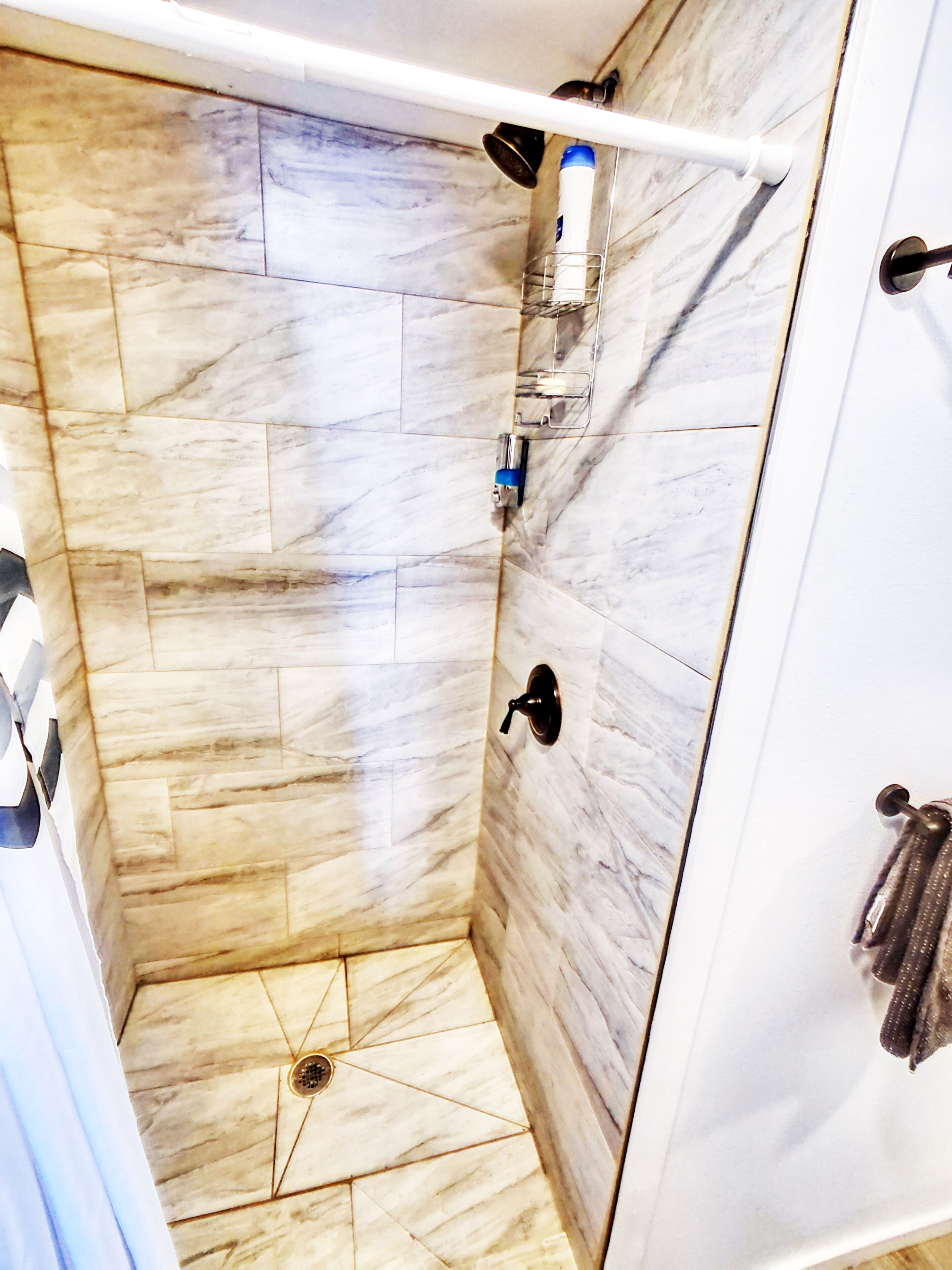 A shower with a marble floor and a white door.
