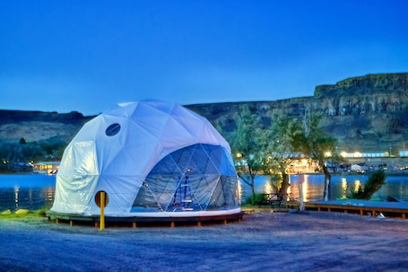 A geodesic dome structure by a lake at dusk.