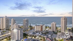 A coastal cityscape with high-rise buildings, a beach, and a clear sky. - Chevron – 3 Bedroom Superior Unit With Ocean Views (Surfers Paradise)