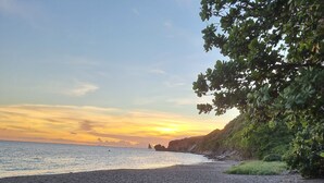 A boat on a sandy beach with a sunset in the background. - Building (Les Anses-d'Arlet)