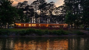 Una cabaña junto al lago con comedor con vistas al agua, rodeada de árboles.