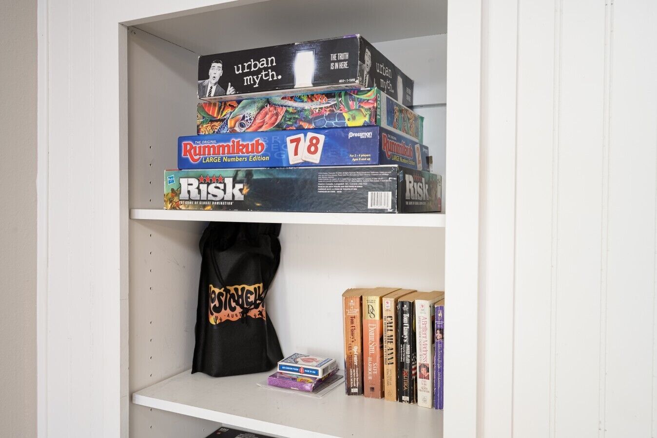 A shelf with board games, a tote bag, and books.