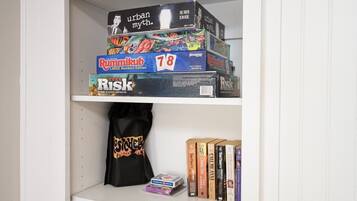 A shelf with board games, a tote bag, and books.