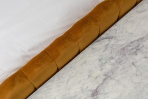Una cama con sábana blanca y cabecera marrón.