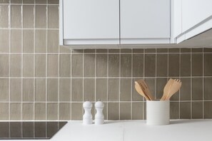 Una cocina con armarios blancos, salpicadero de azulejos y encimera blanca.