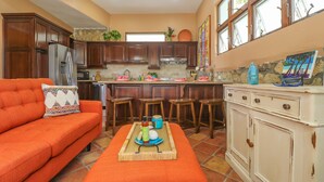 A kitchen with wooden cabinets, a refrigerator, and a dining area with a table and chairs.