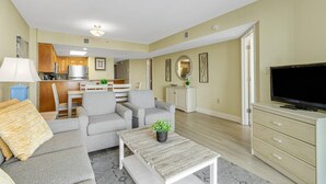 Un salon moderne avec un canapé gris, une table basse et un téléviseur à écran plat posé sur un meuble.