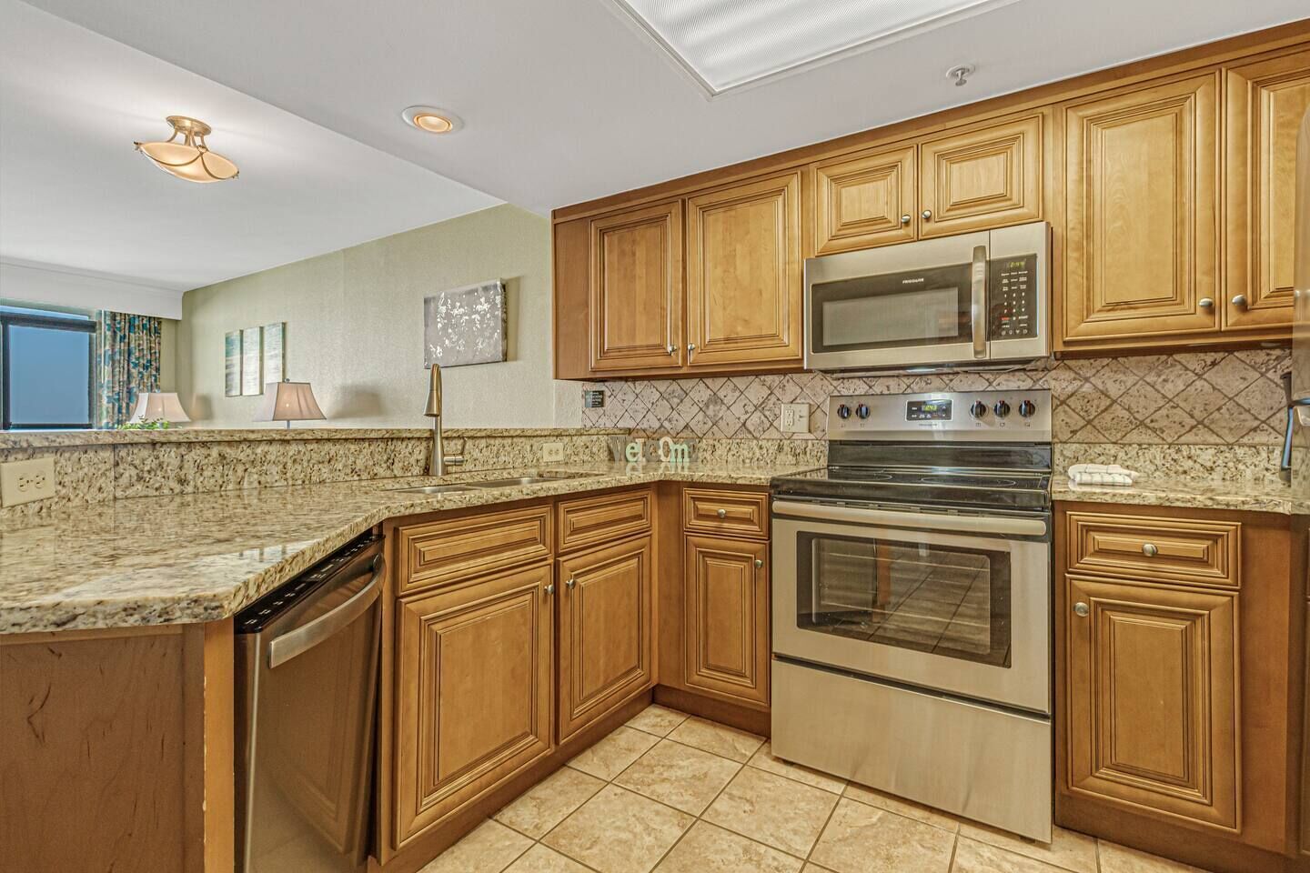A kitchen with wooden cabinets, a stainless steel microwave, and a built-in oven.