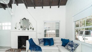 A modern living room with a white sofa, blue cushions, a glass coffee table, and a fireplace. - Bike to Beach-Spacious With Patio BBQ Plus Game Room (Hallandale Beach)