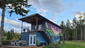 A colorful house with a deck, a staircase, and a door. - Modern container cabin on 13 acre country estate (Sequim)