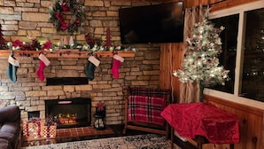 Una sala de estar acogedora con chimenea de piedra, un árbol de Navidad y adornos festivos.