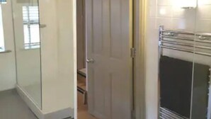 Ein Flur mit Glastür zu einem Zimmer, Holzboden und einem Metallradiator.