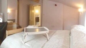 Ein Hotelzimmer mit Bett, Nachttisch, Spiegel und Wandleuchte.