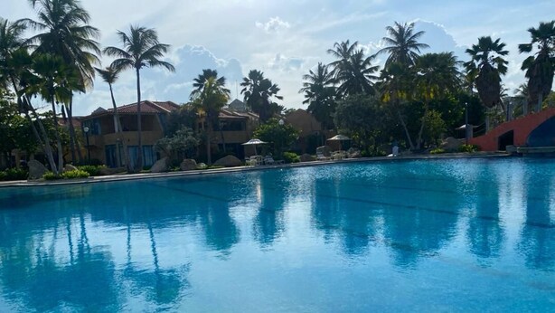 Una piscina azul clara rodeada de palmeras y edificios.