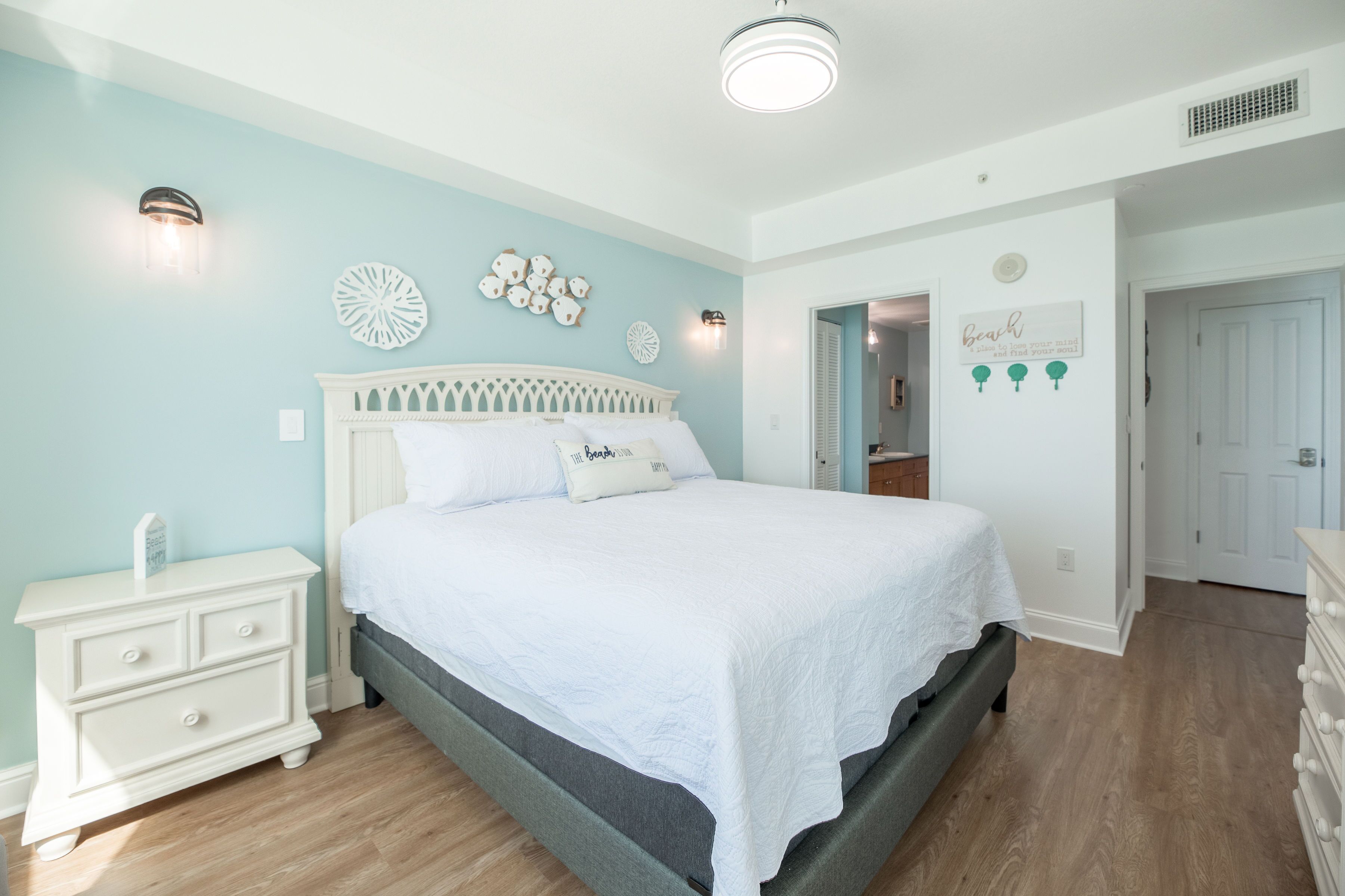 Un dormitorio con cama, mesita de noche, cómoda y decoración mural.