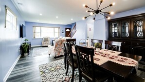 Uma área de refeições com mesa de madeira escura, toalha de mesa estampada e cadeiras combinando.