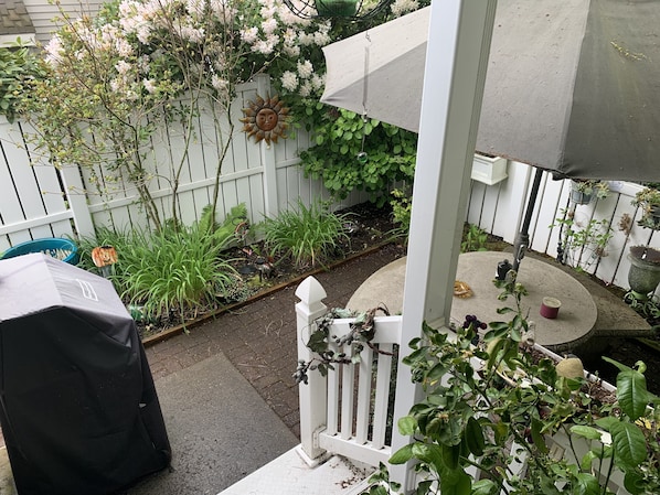 Enjoy an outdoor space with a barbecue grill, potted plants, and a small table for dining or relaxation.