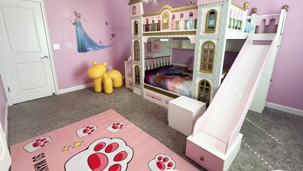A child's bedroom with a castle bed, a slide, and a wall mural.