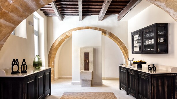 A spacious room with a high arched doorway, dark wooden cabinets, and a marble countertop. - Azade Chania (Chania)