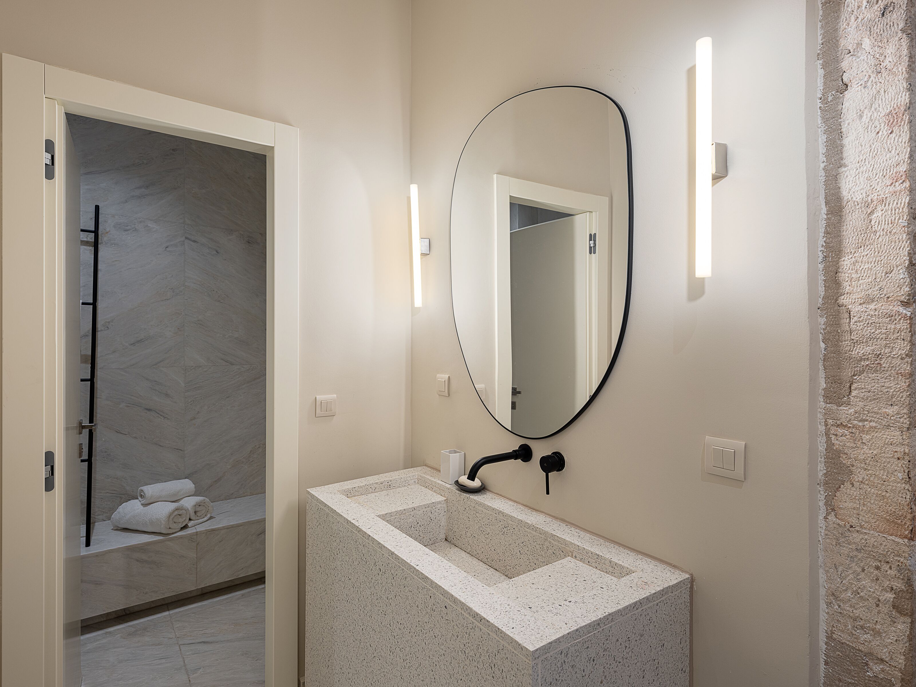 Un baño con lavamanos de mármol, un espejo grande y un perchero para toallas.