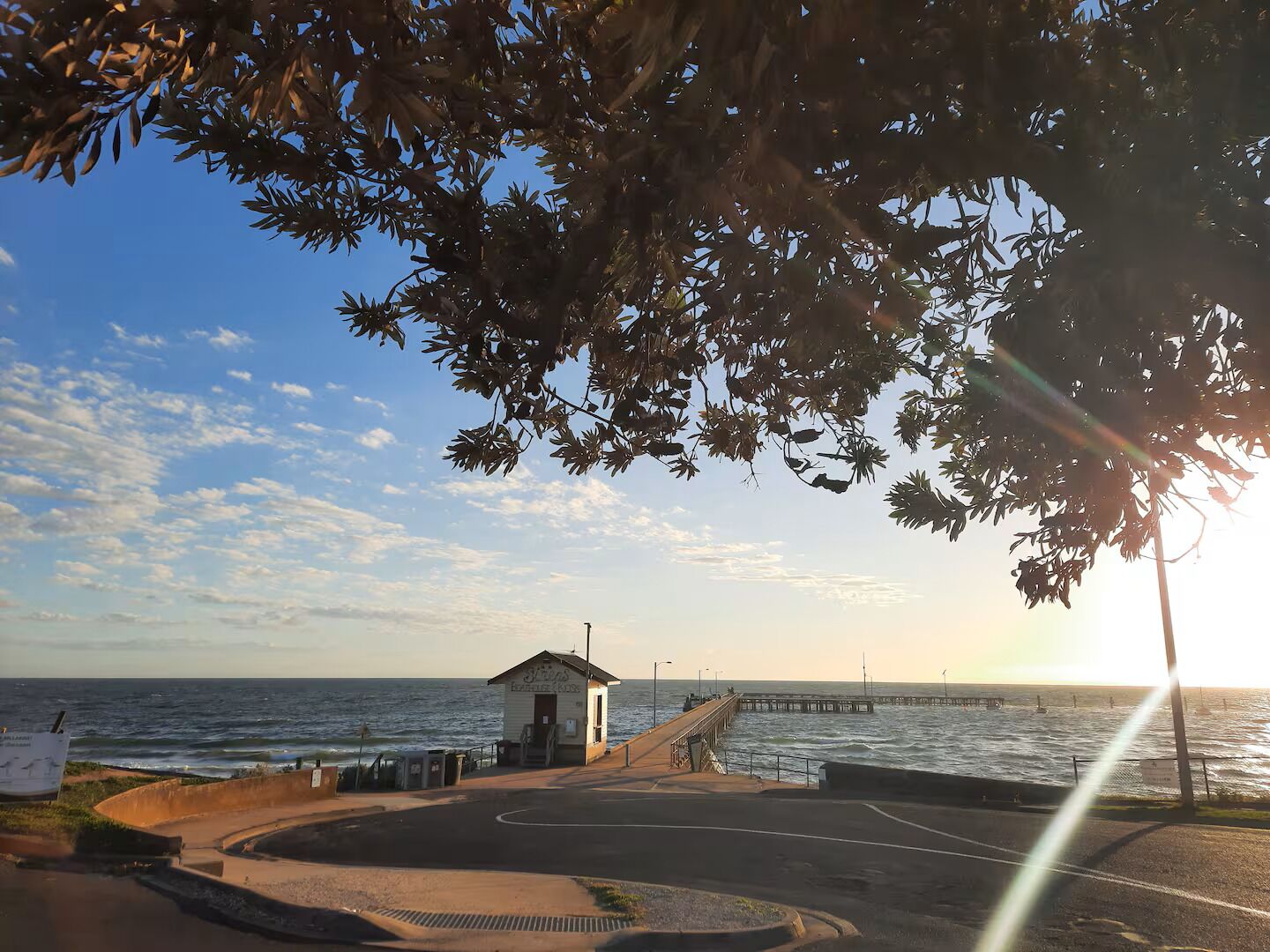 A coastal scene with a pier extending into the sea, a small building labeled 'Fiji's Beach House,' and a clear sky.