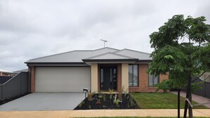 Een modern huis met twee verdiepingen, een garage, een voortuin en een verzorgd gazon.