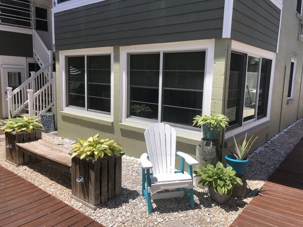 A house with a deck, a white chair, and potted plants.